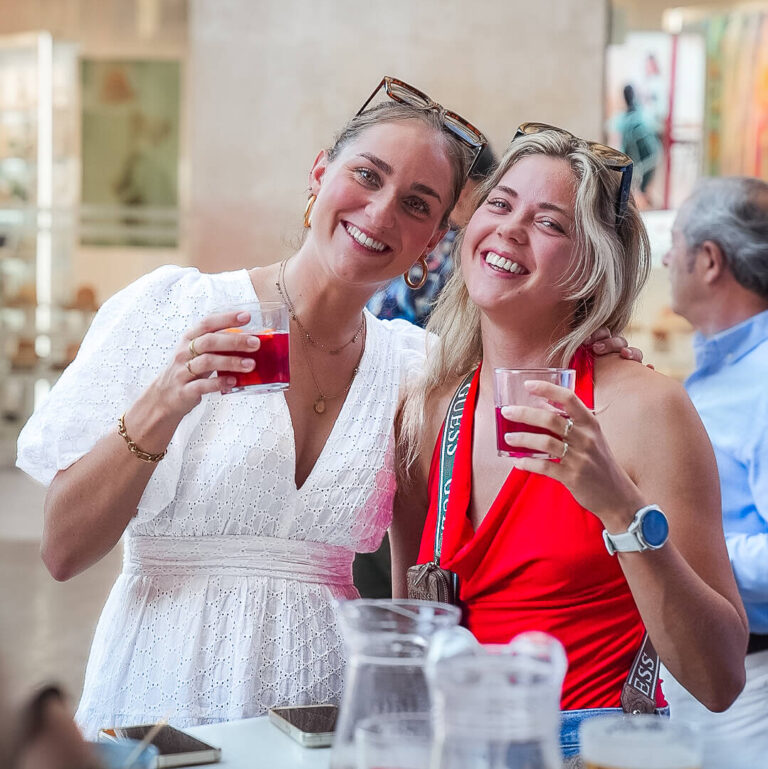 Twee lachende vrouwen proosten samen tijdens een borrelmoment
